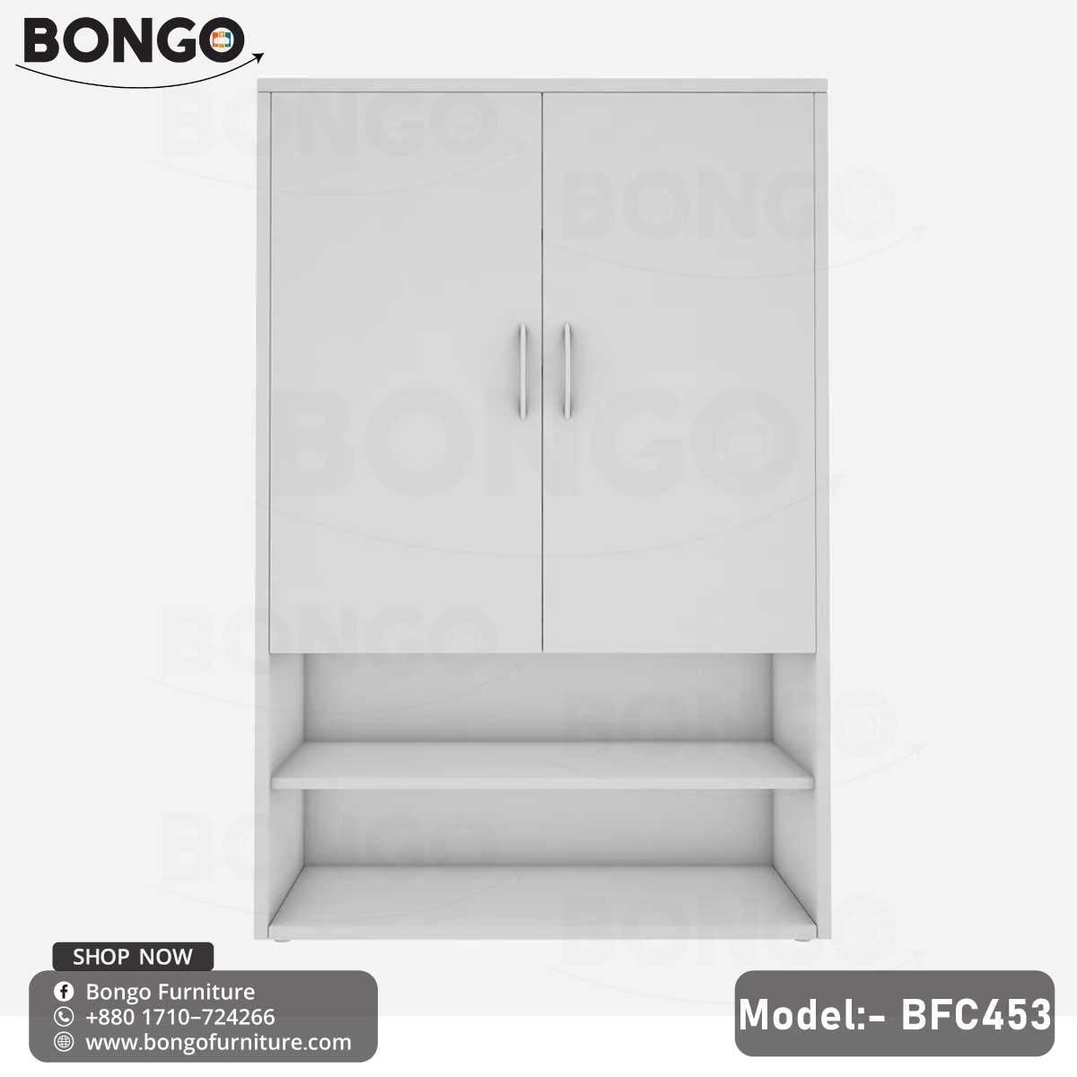 A white footwear shoe rack with multiple compartments, placed against a grey wall with a black shelf on top of it, displaying various shoes and a decorative plant.