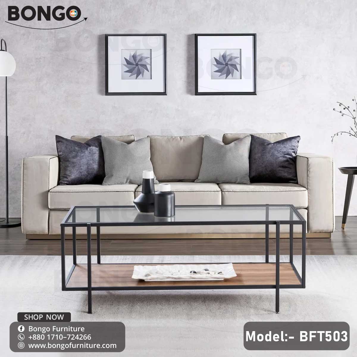 A modern coffee table with a clear glass top, black steel frame, and a wooden shelf underneath. The table is placed in a living room setting with a sofa and cushions in the background.