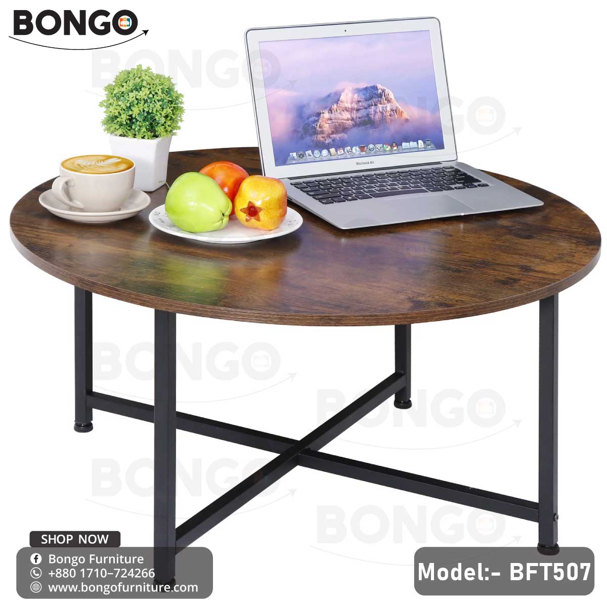 An industrial-style round coffee table from BONGO, featuring a rustic dark wood-grain top and a black metal base with an X-stretcher. The table is shown in a living room setting in front of a gray sofa, styled with books, a vase, and a coffee cup.