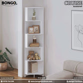 A white corner shelf with five tiers, featuring various decorative items such as books, a teddy bear, and framed pictures. The shelf is positioned in a corner of a room with a plant and a wall drawing in the background.