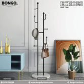 A promotional image shows a modern black metal hall tree with a round white base, standing in an entryway. A blue robe, a light-colored hat, and a tan backpack hang from its various hooks. The hall tree is set against a white brick wall, next to a large window on the left and a small potted plant on the right. The flooring is light-colored wood. In the top corners of the image are the brand logos "BONGO" and "ECHOES Hall Tree".