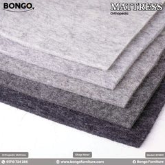 A promotional image from BONGO for an orthopedic mattress, showcasing a stack of thick felt sheets. The sheets are layered to display a color gradient, ranging from light gray on the top layer to dark charcoal gray on the bottom layer, with the fibrous texture of the felt visible. A promotional image from BONGO for an orthopedic mattress, showcasing a stack of thick felt sheets. The sheets are layered to display a color gradient, ranging from light gray on the top layer to dark charcoal gray on the bottom layer, with the fibrous texture of the felt visible.