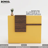 A promotional image of the "MINAL Reception Desk," a modern and compact front desk. The desk features a bold two-tone design, combining a dark wood grain for the main work surface and storage pedestal, with a bright yellow-gold frame that wraps around the side and back. The wrap-around frame creates a raised, multi-level transaction counter. The desk is shown with a small laptop and a decorative plant on top, set against a plain grey background. The "BONGO" brand logo is in the top-left corner.