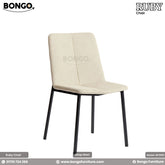 A promotional image of the 'Chair RUBY', a modern dining chair with a slim silhouette. The chair is upholstered in a light cream fabric and features a central vertical seam on its seat and back. It stands on four slender, angled black metal legs.