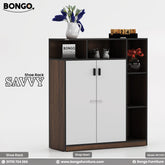 A product image of the "SAVVY Shoe Rack," featuring a dark wood grain frame and shelves. The modern cabinet has two central white doors with vertical black handles, contrasted against the dark wood. It is surrounded by open, cubby-style shelves on the top and right side. The shelves are styled with decorative items, including a vase of purple flowers, a pair of miniature sneakers, a wooden block calendar, and a vase of red flowers. The "BONGO" and "SAVVY" brand names are displayed on the left of the image.