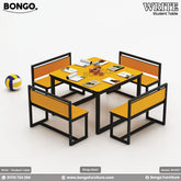 A set of student furniture including a rectangular table with a yellow tabletop and black steel frame, surrounded by four orange benches with black steel frames. There is also a basketball and a soccer ball next to the furniture.