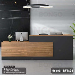 A contemporary office desk with a wood finish and black detailing, equipped with a computer monitor and keyboard, set against a modern office background.