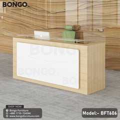 A modern reception desk from BONGO with a light wood-grain frame. The front of the desk features a large, white inset panel, and a raised glass shelf serves as the transaction counter. The desk is shown in a modern lobby setting.