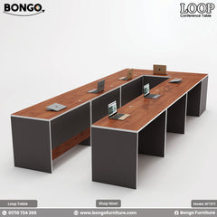 A modular conference table named Loop with a brown tabletop, gray legs, and multiple chairs around it.