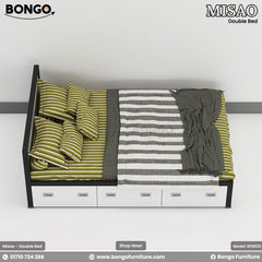 A top-down view of a modern platform bed with a black frame and a row of three white storage drawers along its side. The bed is neatly styled with green and beige striped bedding, a variety of matching pillows, and a folded gray and white striped throw blanket at the foot.