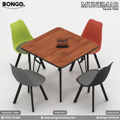 A square dining table with a Water Resistant Strong Laminated Board  laminated top and black metal base, surrounded by four chairs in green, red, and gray.