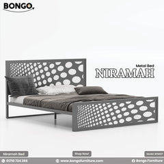 A promotional image of the "NIRAMAH Metal Bed" by Bongo, presented in a grey and white color scheme. The modern metal bed frame is a solid medium-grey color. The tall, rectangular headboard and matching lower footboard feature a decorative laser-cut pattern of circles that gradually increase in size from one side to the other. The grey cutout panel is backed by a solid white panel, making the gradient polka-dot pattern stand out in high contrast. The bed is styled with dark grey and brown bedding.