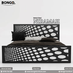 A promotional image of the "NIRAMAH Metal Bed" by Bongo. The modern bed frame is constructed from black metal and features a distinctive design. Both the tall, rectangular headboard and the matching lower footboard have a decorative laser-cut pattern of circles that gradually increase in size from left to right, creating a gradient polka-dot effect. The bed is styled with dark brown and grey bedding and is set against a plain, light grey background.