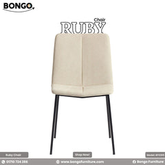 A promotional image of the 'Chair RUBY', a modern dining chair with a slim silhouette. The chair is upholstered in a light cream fabric and features a central vertical seam on its seat and back. It stands on four slender, angled black metal legs.