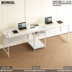 White office desk with laptops and accessories in a room with wooden flooring and white walls.